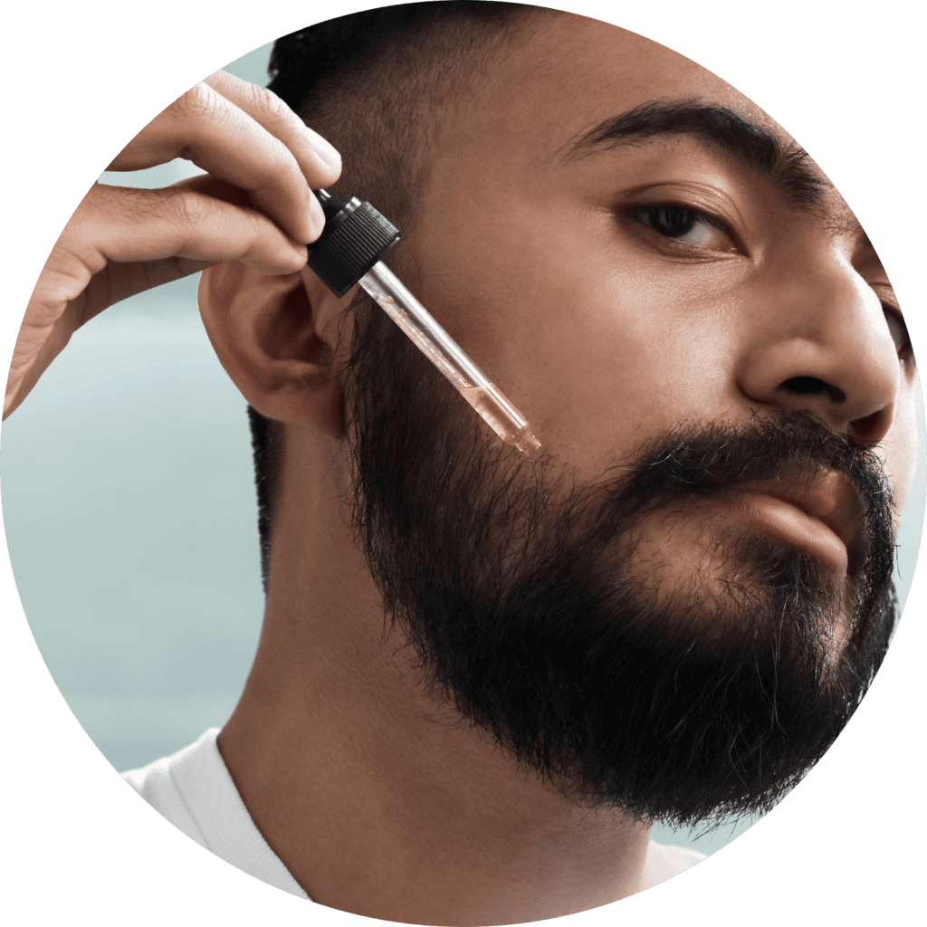 A man putting a serum on his beard.