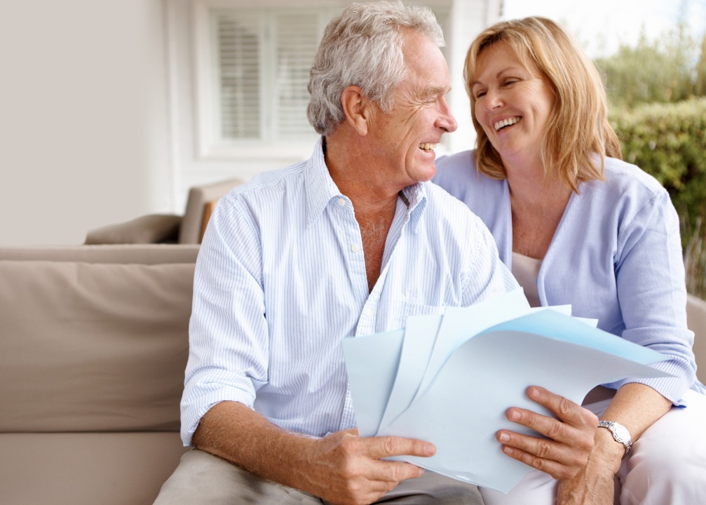 A couple smiling while reading paperwork.