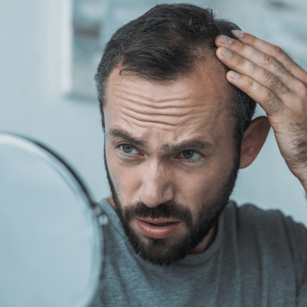 A man checking a bald spot in a hand mirror.